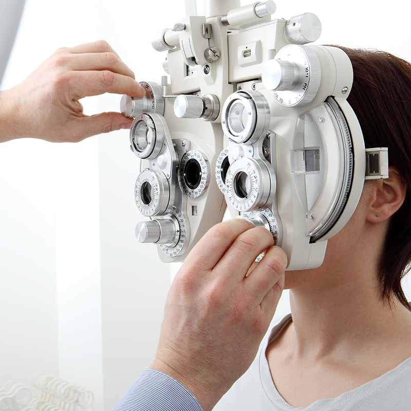 Optometrist adjusting a phoropter on a patient