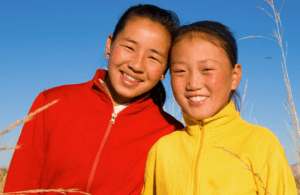 Two young Mongolian girls outdoors and smiling