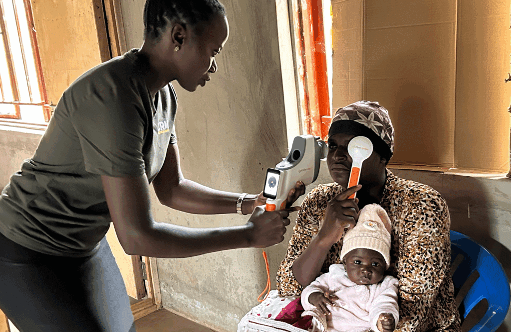 A vision mission volunteer in rural Uganda measures a patient's refractive error with QuickSee Free